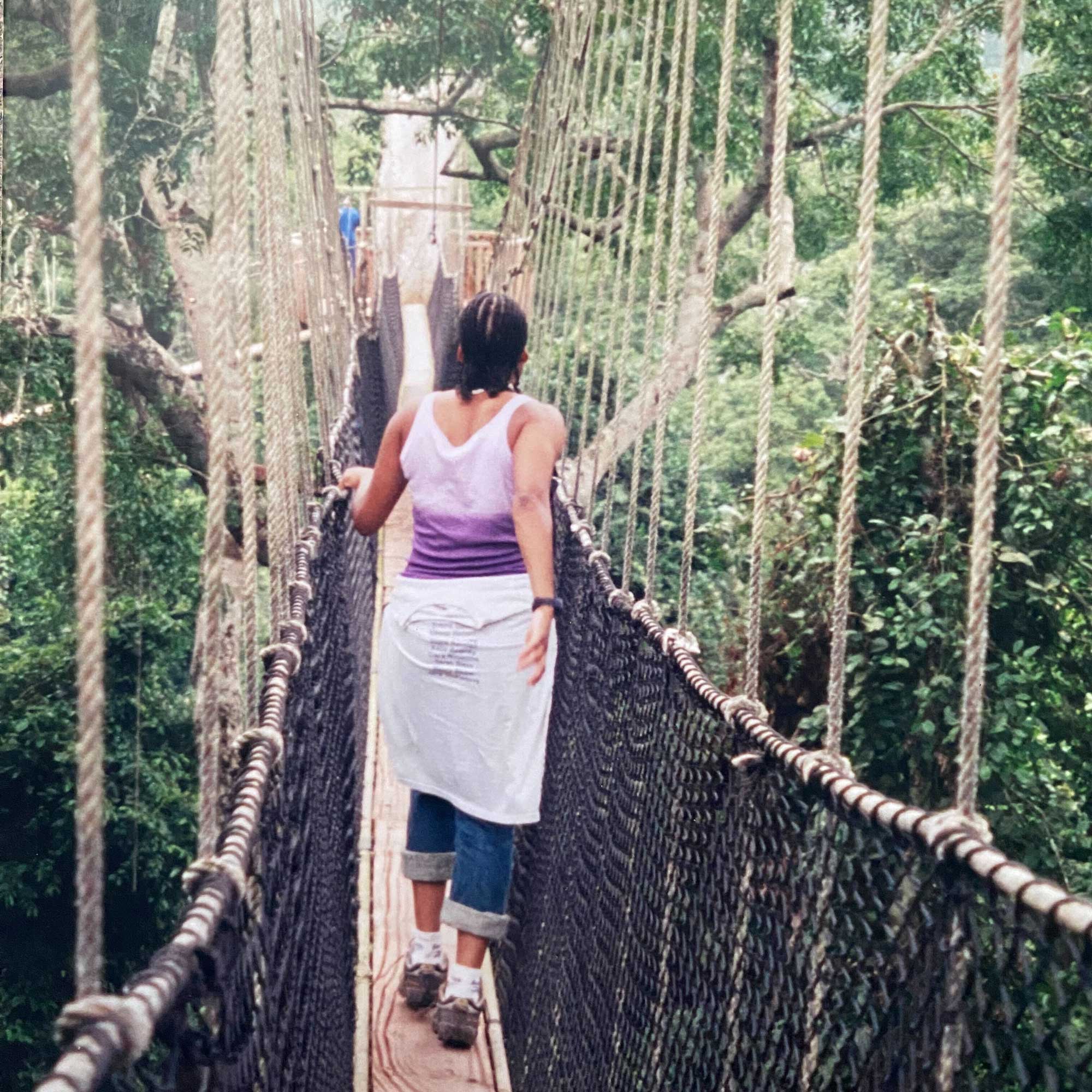 Back of AYLF Staff member Mickeeya walking across a hanging bridge in Ghana